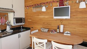 A kitchen with white cabinets, a microwave, a wooden table, and a TV mounted on the wall. - Studio for 2 with balcony in the center of Avoriaz (Avoriaz)