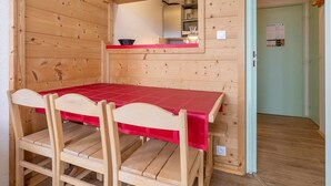 A wooden interior with a red table and chairs, a mirror, and a door with a welcome sign. - South-facing Apartment 5 pers, balcony Avoriaz (Avoriaz)