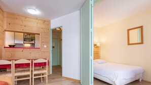 A compact room with a kitchenette, a single bed, and a wooden dining table. - South-facing Apartment 5 pers, balcony Avoriaz (Avoriaz)
