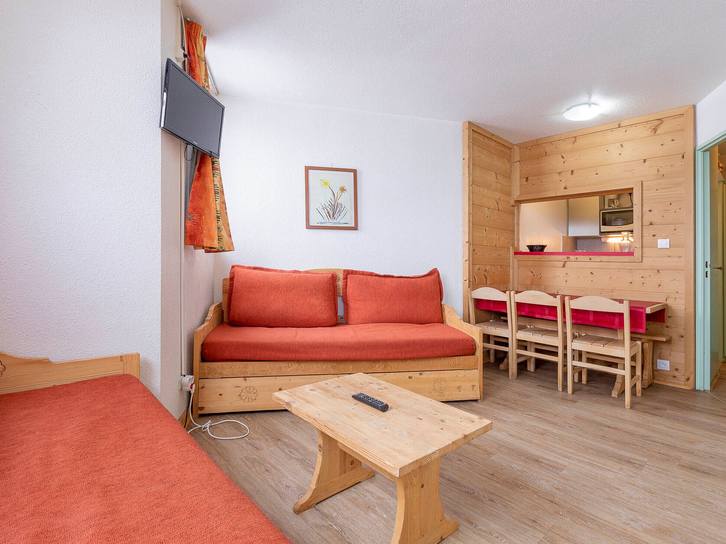 A cozy room with a wooden sofa, a small wooden table, and a dining area with chairs and a table.