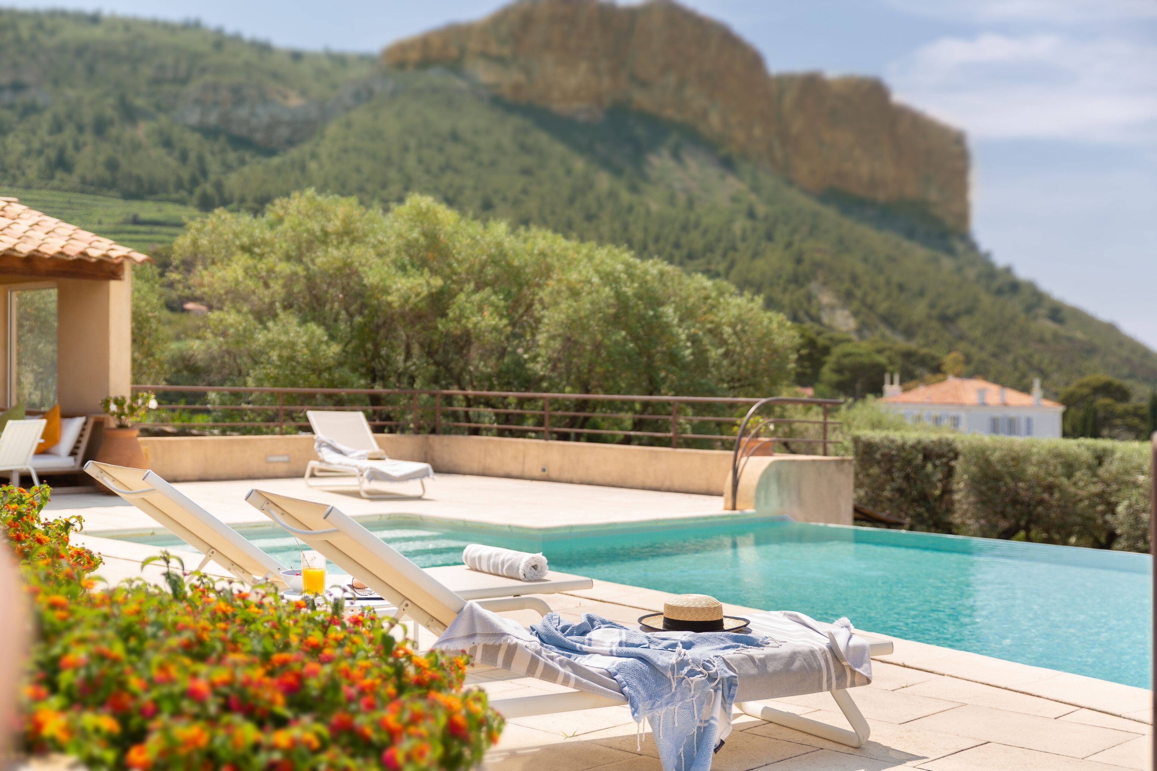 A poolside area with lounge chairs, a pool, and a mountain backdrop.