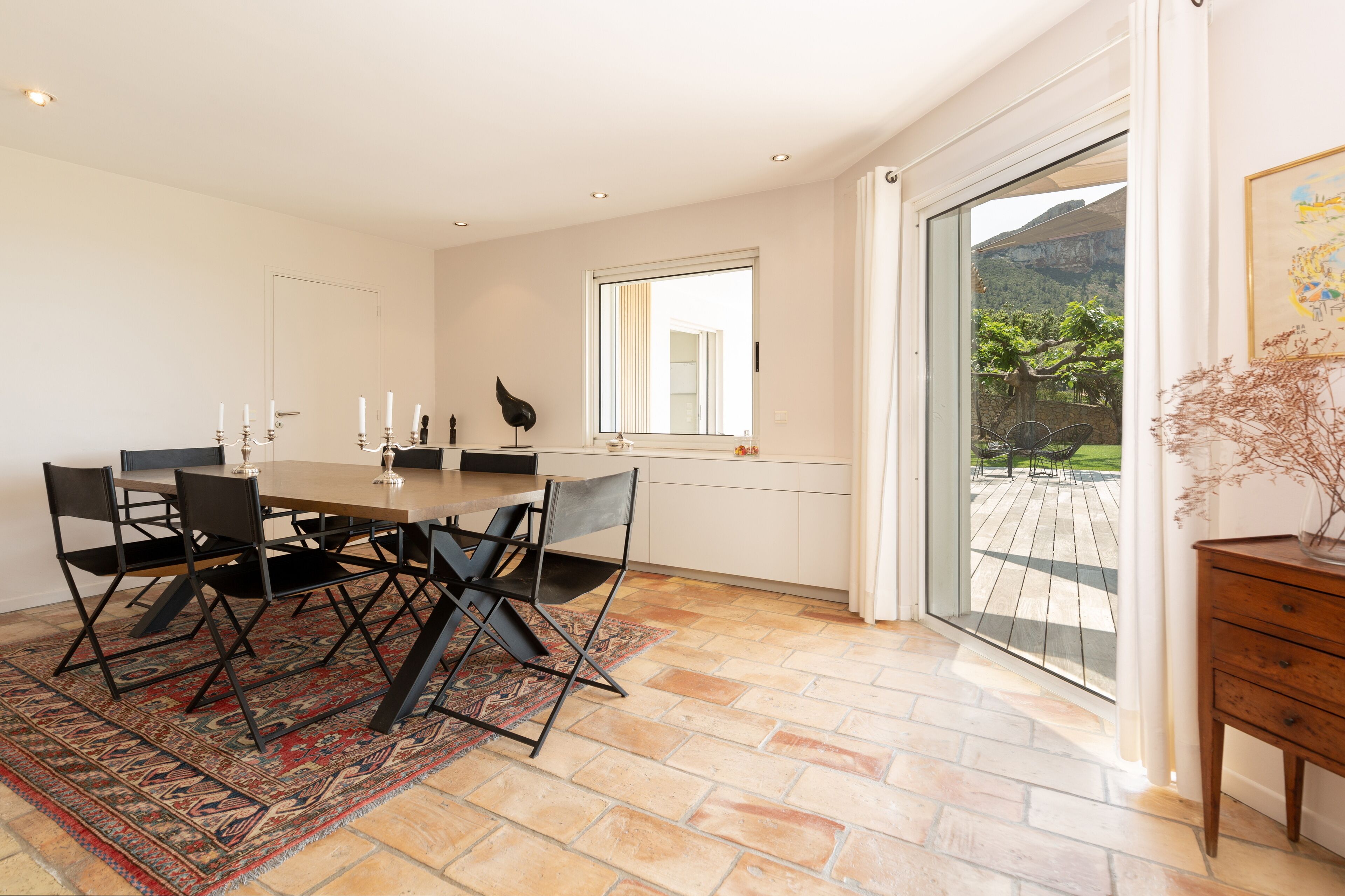 Un espace repas comprenant une table, des chaises et donnant sur un balcon avec une vue sur les montagnes.