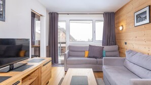A modern living room with a sofa, a coffee table, a TV, and wooden walls. - Beautiful 2-room apartment for 4 in Avoriaz, Southeast balcony (Avoriaz)