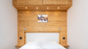 A bedroom with a wooden headboard, a bed with white bedding, and a small painting above the headboard. - Beautiful 2-room apartment for 4 in Avoriaz, Southeast balcony (Avoriaz)