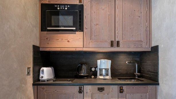 A compact kitchen with wooden cabinets, a built-in oven, a toaster, a coffee maker, and a sink. - Charming renovated apartment 2 rooms, balcony, WiFi (Avoriaz)