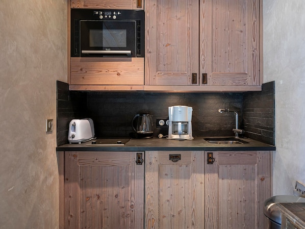 A compact kitchen with wooden cabinets, a built-in oven, a toaster, a coffee maker, and a sink. - Charming renovated apartment 2 rooms, balcony, WiFi (Avoriaz)