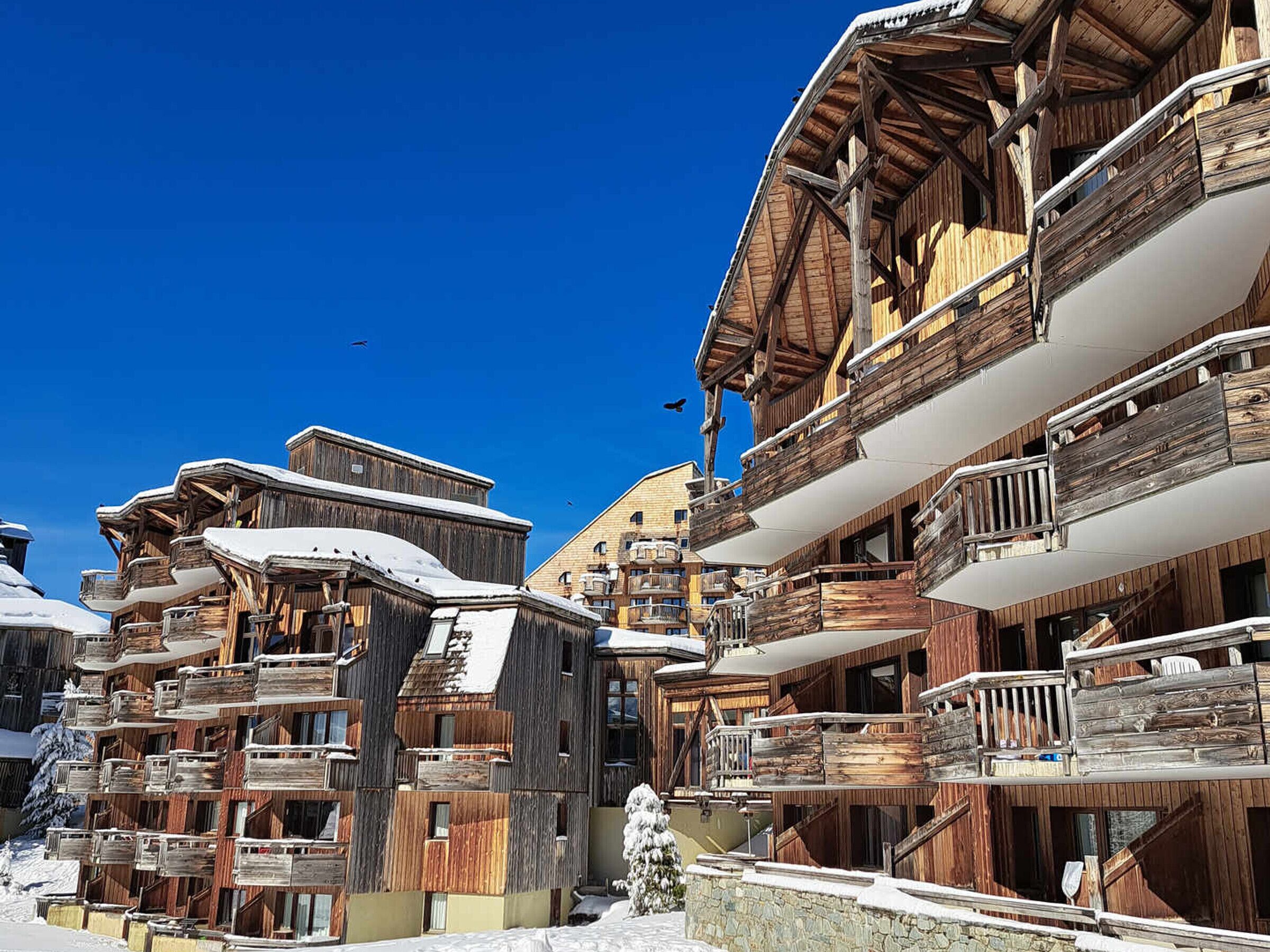 Un gruppo di edifici in stile chalet in legno, con balconi e neve sui tetti, che suggerisce un paesaggio invernale.