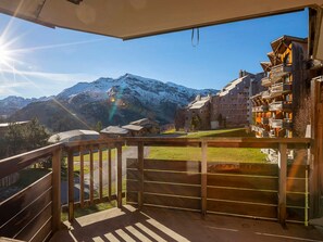 Un balcon offrant une vue sur des montagnes enneigées et des bâtiments traditionnels en bois.