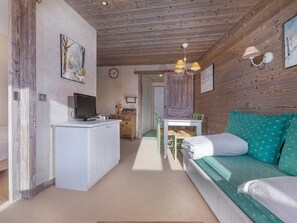 A cozy room with a bed, a desk with a computer, a dining table, and a wooden ceiling. - Charming renovated apartment 2 rooms, balcony, WiFi (Avoriaz)