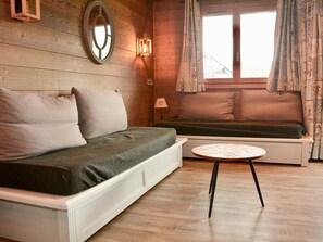 A cozy room with a sofa, a small round table, and a window with curtains.
