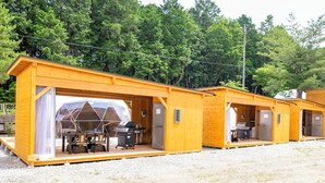 A row of wooden cabins with open fronts, each featuring a grill and a dining table. - Glamping Hoshigaminomori (Nakatsugawa)