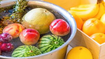 Eine Schüssel mit frischen Früchten, darunter Wassermelonen, Pfirsiche, Pflaumen und eine Ananas.