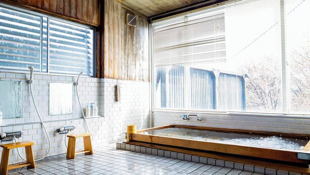 A bathroom with a wooden bathtub, white tiled walls, a window with blinds, and a small wooden stool. - Glamping Hoshigaminomori (Nakatsugawa)