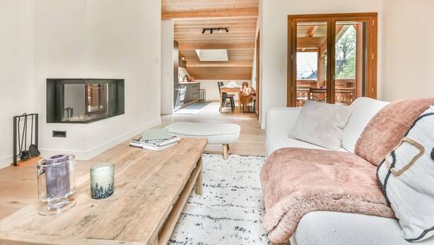 A modern living room with a fireplace, a wooden coffee table, and a cozy sofa.