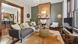 A modern living room with a fireplace, a sofa, a coffee table, and a TV. - Unwind and indulge in this spacious and stylish Short North retreat. (Columbus)