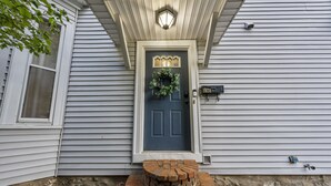 A house with a dark blue front door, a brick step leading to the entrance, and a light fixture above the door. - Unwind and indulge in this spacious and stylish Short North retreat. (Columbus)