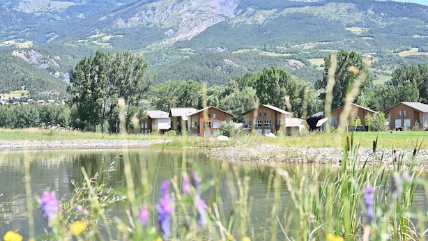 A lakeside view of a mountain range with wooden cabins. - Modern apartment with terrace and private parking (Barcelonnette)
