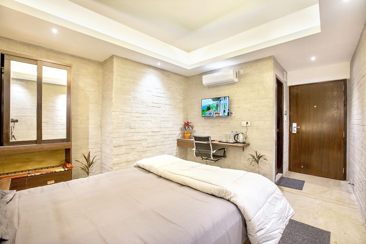 Ein modernes Hotelzimmer mit einem großen Bett, einem Schreibtisch, einem Fernseher und einer Holztür.