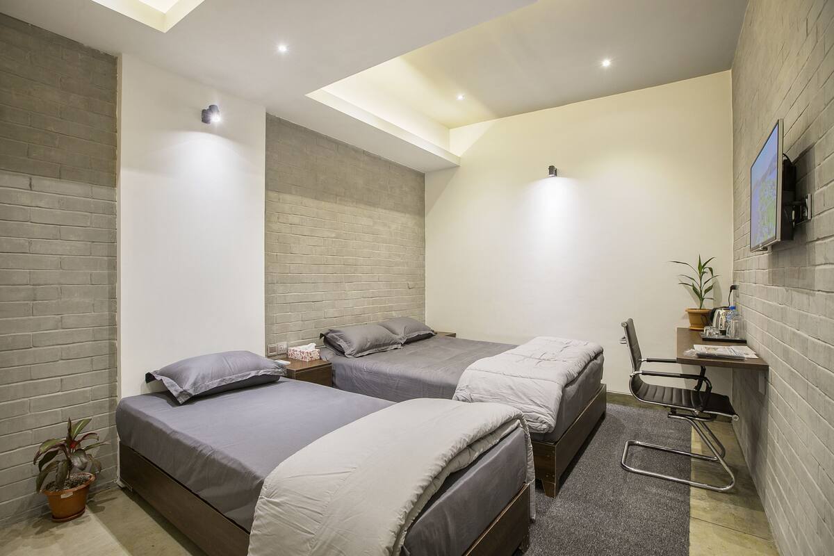 Ein kleines Hotelzimmer mit zwei Betten, einem Schreibtisch und einem Stuhl.
