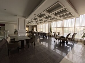 Un amplio vestíbulo de hotel con techo alto, ventanas grandes y un diseño de interiores moderno.