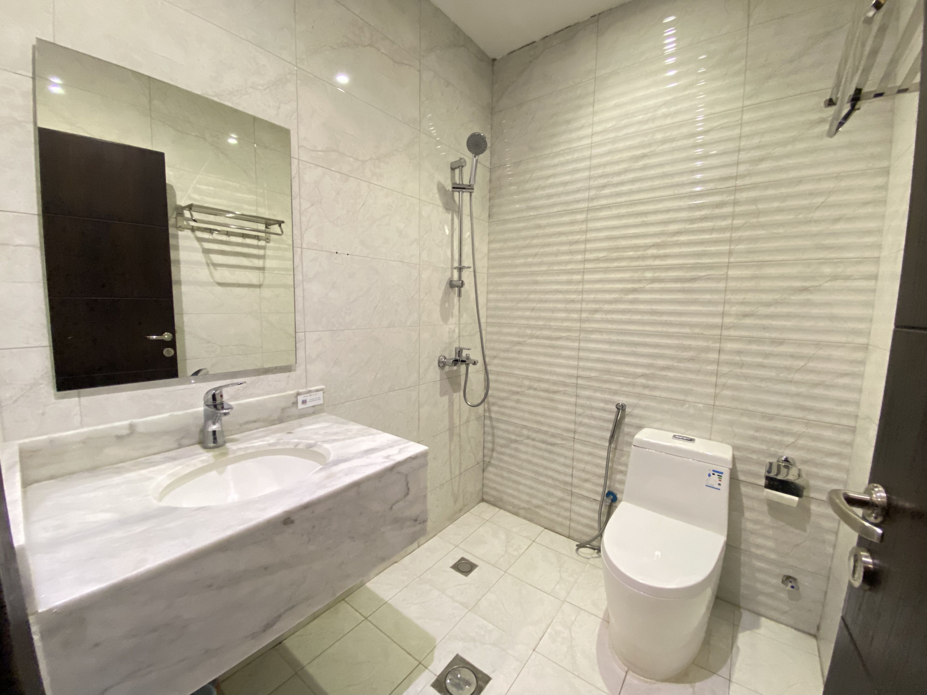 A modern bathroom with a marble sink, a toilet, and a shower.