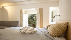 Una camera da letto con un letto, un divano grigio e vista sul verde.
