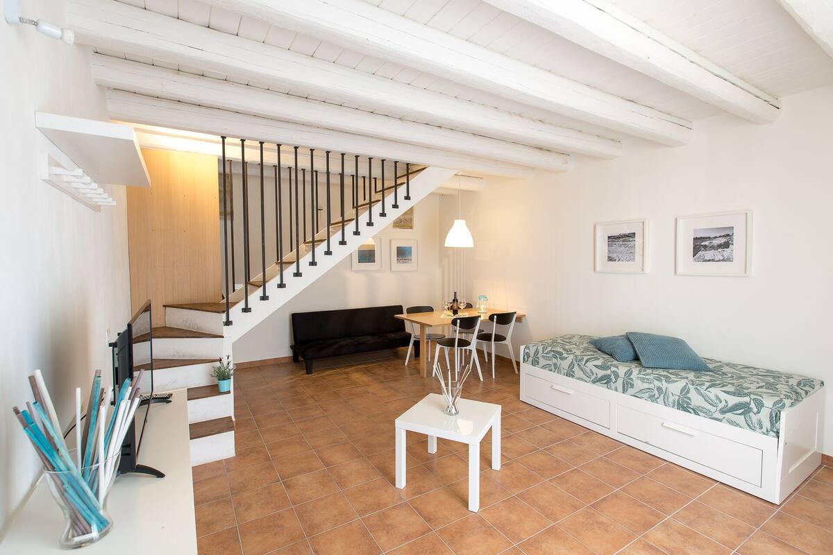 A spacious living area with a staircase, a dining table, and a sofa.