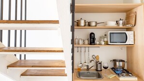 Una cucina compatta con forno a microonde, macchina del caffè e piano cottura a gas.