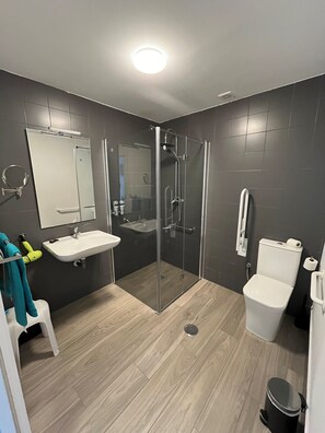 A modern bathroom with a glass-enclosed shower, a sink, and a toilet.