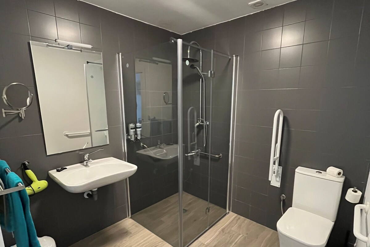Un baño moderno con ducha de vidrio, lavamanos y retrete.