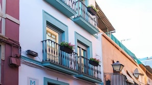 A building with a blue and white facade, a black door, and a sign with the letter 'M'. - APARTAMENTOS MAPAMUNDI (Badajoz)