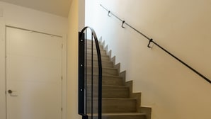 A wooden staircase with a handrail, leading to a white door. - APARTAMENTOS MAPAMUNDI (Badajoz)
