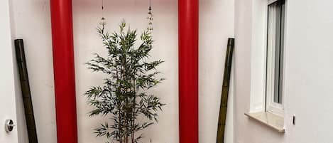 A room with a red torii gate, a bamboo plant, a wooden table, and a black sofa.