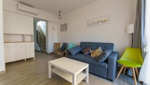 A modern living room with a grey sofa, a white coffee table, and a green chair. There is a staircase leading to another level. - APARTAMENTOS MAPAMUNDI (Badajoz)