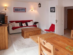 Un salon chaleureux avec un canapé, une table basse en bois et un fauteuil rouge.