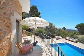A stone building with a pool, outdoor seating, and a view of the landscape.