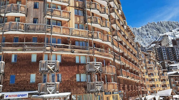 A multi-story hotel with wooden balconies and ski slope views.