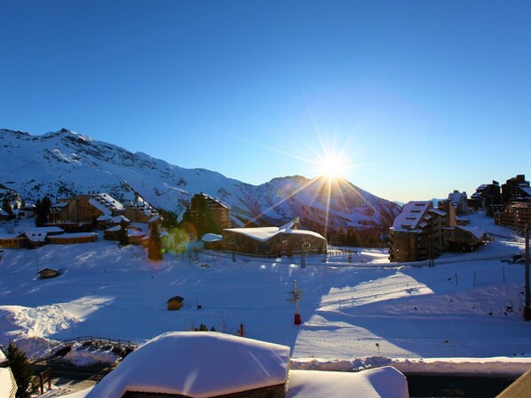 A snow-covered mountain village with traditional wooden buildings, a clear sky, and the sun shining brightly.