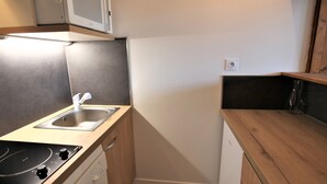 A compact kitchenette with a microwave, sink, and stove.