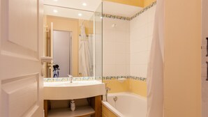 Une salle de bain avec un lavabo, un miroir et une baignoire.