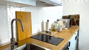 Una cocina moderna con un lavamanos de acero inoxidable, encimera de madera y estufa integrada.