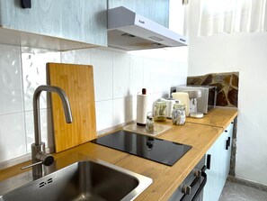 Una cocina moderna con un lavamanos de acero inoxidable, encimera de madera y estufa integrada.