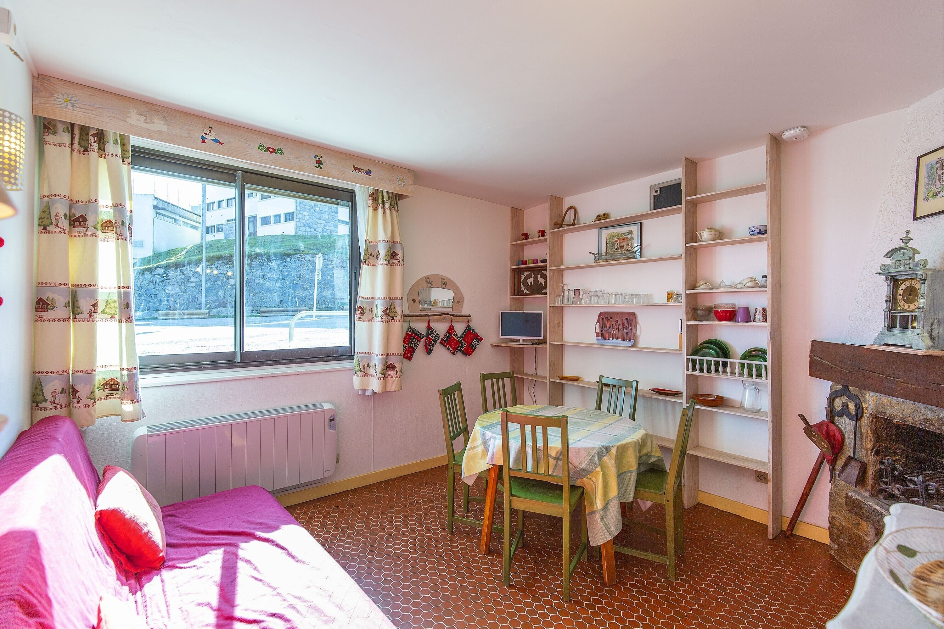 Ein gemütliches Zimmer mit einem Bett, einem Esstisch mit Stühlen, einem Kamin und einem Fenster mit Vorhängen.