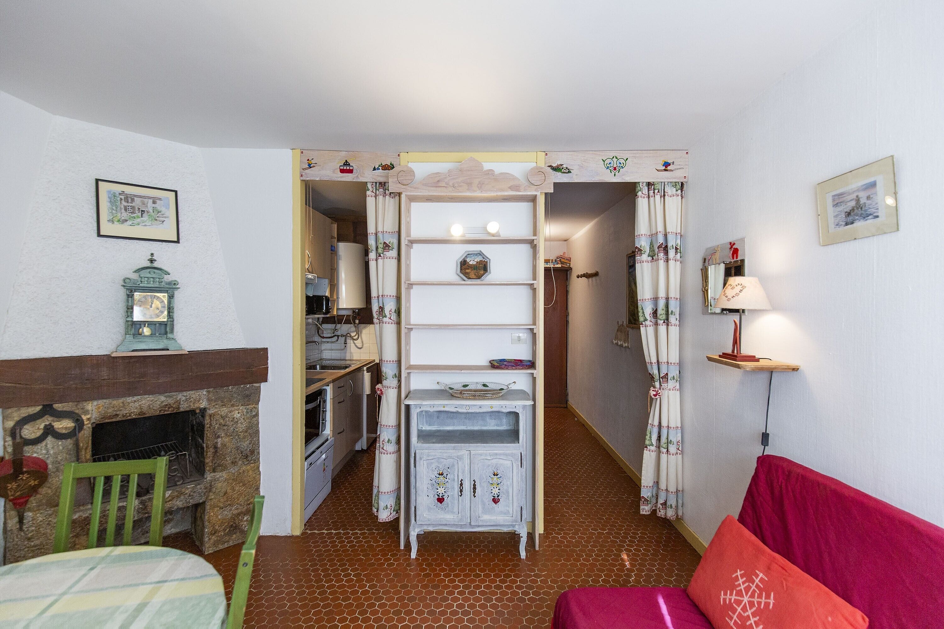 A cozy living room with a fireplace, a dining area, and a hallway leading to a kitchen.