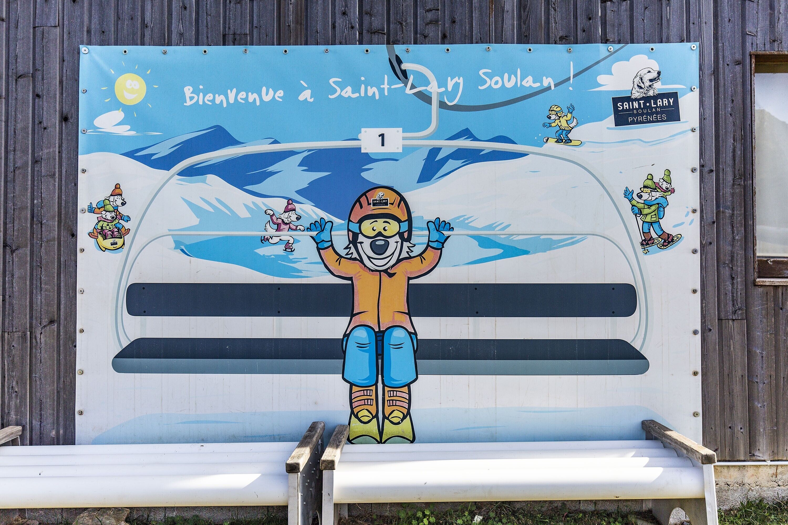 A wall with a colorful mural featuring a skier and a dog, and the text 'Bienvenue à Saint-Lary Soulan!'