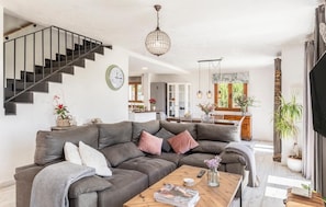 A modern living room with a grey sofa, a wooden coffee table, and a staircase with a black railing.