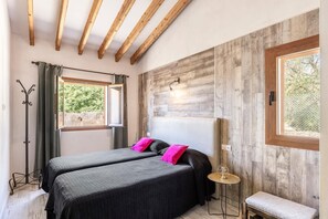 A room with two beds, a window, a coat rack, and a bench. - Villa 'Maria' with Mountain View, Wi-Fi and Air Conditioning (Pollensa)