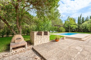 Un jardin avec un four en pierre, une piscine et une pelouse.