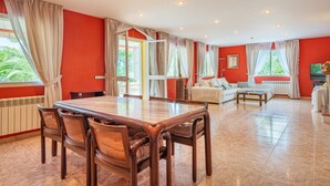Een ruime kamer met een eettafel, stoelen, een bank en een televisie.