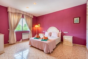 Une chambre à coucher avec un lit, des tables de chevet, une lampe et une fenêtre avec des rideaux.